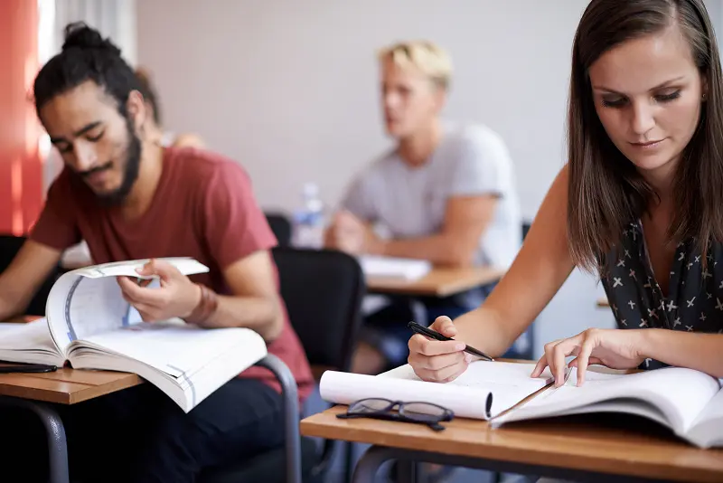 Students studying together in class at wooden desk